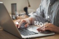 Person arbeitet am Laptop mit digitalen Symbolen für SEO, Analyse und Online-Marketing
