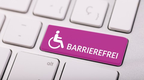 Computertastatur mit einer großen, pinken Taste mit Rollstuhlsymbol und dem Wort „Barrierefrei“, Symbol für digitale Barrierefreiheit.