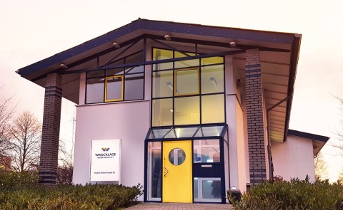 Firmengebäude der Wrocklage Werbewerkstatt in Ibbenbüren.
Außenansicht des Firmengebäudes der Wrocklage Werbewerkstatt mit gelber Eingangstür und großem Glasfassadenbereich.