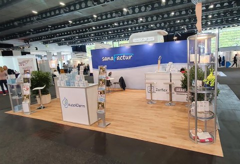 Übersicht über den Messestand von SanaFactur mit Broschüren, Vitrinen und PVC-Fußboden