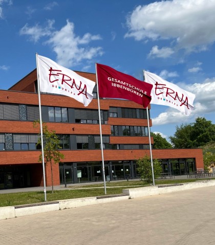 Fahnenanlage mit ERNA-Logo vor der Erna-de-Vries-Gesamtschule – gestaltet von Wrocklage Werbewerkstatt Drei große Fahnen mit Logo der Erna-de-Vries-Gesamtschule, montiert vor dem Schulgebäude – Design und Umsetzung: Wrocklage Werbewerkstatt