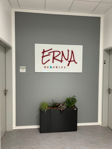 Logo-Schild mit Echtglasveredelung im Eingangsbereich – gefertigt von Wrocklage Werbewerkstatt Eingangsbereich der Schule mit montiertem Acrylschild und ERNA-Logo – hochwertiges Werbemittel von Wrocklage Werbewerkstatt