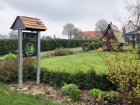 Schild mit Fairytale-Logo auf maßgefertigtem Gestell, im Gartenbereich der Distillery installiert