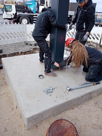 Montage der Trägerkonstruktion für die neue Outdoor Video-Wall mit 30 m² Videofläche bei der Firma Piepenbrock Mitarbeiter befestigen die Trägerstruktur der Outdoor Video-Wall bei Piepenbrock auf dem Betonfundament