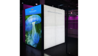 Messestand der Wrocklage Werbewerkstatt mit LED-Beleuchtung und digitaler Grafik. Kubischer Messestand mit leuchtender LED-Wand und farbiger Grafik einer Qualle, sichtbar Website-URL.