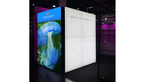Kubischer Messestand mit leuchtender LED-Wand und farbiger Grafik einer Qualle, sichtbar Website-URL.