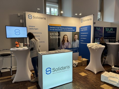 Solidaris auf Karrieremesse – moderner Stand mit LED-Counter und Beratung vor Ort Messestand von Solidaris mit beleuchtetem Counter und Infomaterial bei einer Karrieremesse