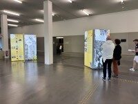 Studierende betrachten LED-Säulen-Ausstellung der Universität Osnabrück zum 50-jährigen Bestehen Personen gehen durch eine Ausstellung mit beleuchteten LED-Säulen anlässlich des Unijubiläums