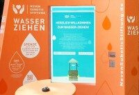 Nahaufnahme der orangefarbenen Spendenstation der Neven Subotic Stiftung mit Infoscreen.