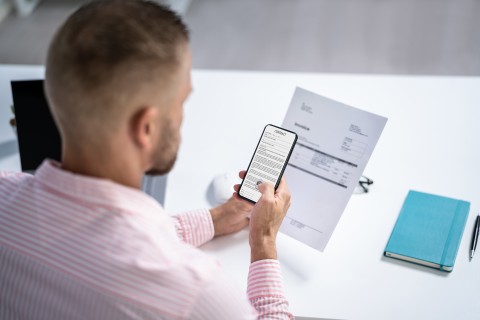 Ihre zentrale Sammelstelle für alle projektbezogenen Dokumente in einer App. Mann nutzt Smartphone-App zum Fotografieren und digitalen Speichern von Papierdokumenten am Arbeitsplatz.