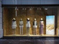 Schaufenster mit mehreren Schaufensterpuppen und einer vertikalen LED-Leuchtwand mit Landschaftsmotiv