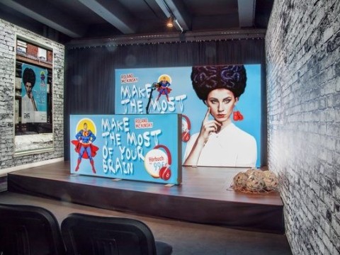 Loftartige Location mit Menschen am Tisch und LED-Leuchtwand mit buntem Motiv