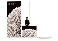 Frau beim Aufbau eines Expand Roll-Up Banners mit modernem grafischen Design aus weißen Rollen auf schwarzem Hintergrund