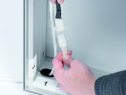 Stromanschluss einer LED-Leuchtwand – einfache Verkabelung für Messe- und Displaytechnik Hand steckt Stromkabel in den Anschluss einer LED-Leuchtwand mit Aluminiumrahmen