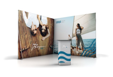 Zwei große Plakatwände mit Urlaubsmotiven und ein Promotiontisch mit Wellenmuster.