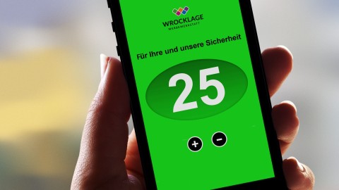 Person hält Smartphone mit grüner App Oberfläche, zeigt 