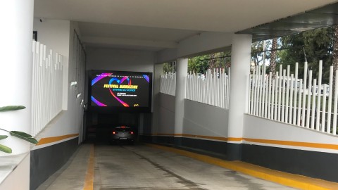 Ein Auto fährt durch einen Tunnel mit einem digitalen Plakat Videowand über einem Festival.