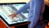 Ein Mann bedient einen großen Touchscreen mit einer digitalen Benutzeroberfläche.
