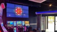 Spielautomaten mit beleuchtetem J-Logo im Hintergrund Computerspielautomaten mit bunten Bildschirmen und einem großen beleuchteten Logo mit einem J im Hintergrund.