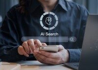 Frau nutzt Smartphone für KI-gestützte Suche, Laptop im Hintergrund