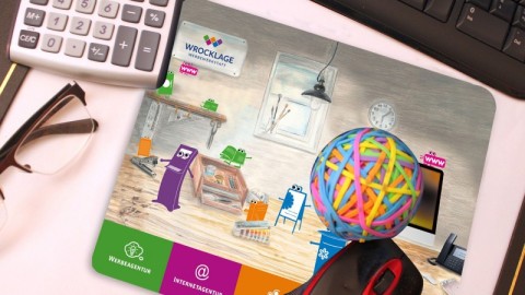 Bedrucktes Mousepad mit farbigem Design auf einem Schreibtisch mit Tastatur, Taschenrechner und Büroaccessoires