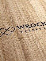 Graviertes Wrocklage-Logo auf heller Holzoberfläche als Beispiel für Materialveredelung und Branding