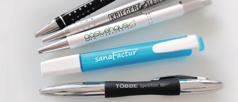 Mehrere bedruckte Kugelschreiber in verschiedenen Farben mit Firmenlogos, Beispiel für personalisierte Werbemittel