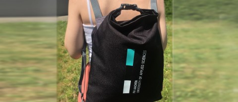 Person trägt schwarzen Turnbeutel mit Aufdruck, Beispiel für funktionales Werbemittel im Freizeitbereich