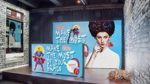 Leuchtwand im Loft – stilvolle Präsentation für Events und Gastronomie Loftartige Location mit Menschen am Tisch und LED-Leuchtwand mit buntem Motiv