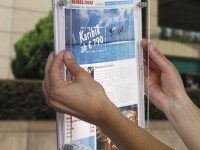 Person wechselt ein Exposé in einem transparenten LED-Schaufensterrahmen, Beispiel für einfach zu bedienende Präsentationssysteme